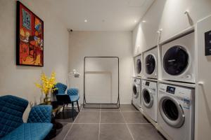 a laundry room with a washing machine and blue chairs at SOON DESIGNER HOTEL Xi'an Drum Tower & YONGNING Gate Branch in Xi'an
