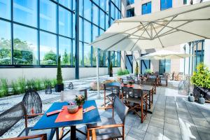 a restaurant with tables and chairs and umbrellas at LOGINN Hotel Leipzig in Leipzig