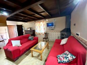 Casa Rural EL CANAL 2LM في كامبيوس: غرفة معيشة مع أريكة حمراء وطاولة