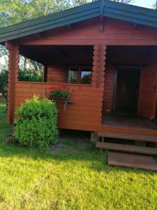 a log cabin with a deck in the grass at Szyper pokoje i domki in Władysławowo