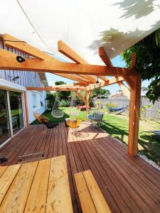 una terraza de madera con sillas y un columpio en La Maison Bisca, en Biscarrosse-Plage