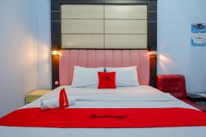 a bedroom with a bed with red pillows on it at RedDoorz Plus Syariah near Stasiun Pekalongan 2 in Pekalongan
