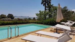 a swimming pool with two chairs and an umbrella at Santa Igia - Country House in Cagliari