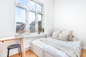 a white bedroom with a bed and a desk and window at Pieni Roobertinkatu Small 13 in Helsinki