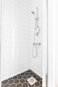 a bathroom with a shower with a tiled floor at Pieni Roobertinkatu Small 13 in Helsinki