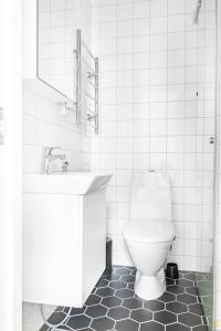 a white bathroom with a toilet and a sink at Pieni Roobertinkatu Small 13 in Helsinki
