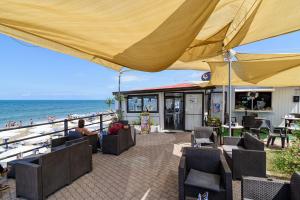 a beach bar with a large yellow umbrella and the ocean at B&B Il Colore del mare in Agropoli