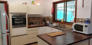 a kitchen with white cabinets and a microwave on a counter at Mermaid Beachside Accommodation in Denham