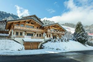 un gran edificio de madera con nieve en el suelo en APARTMENT TRABETS 2 - Alpes Travel - LES HOUCHES - sleeps 8, en Les Houches