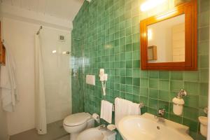a green tiled bathroom with a sink and a toilet at Sopra il Limoneto in Cetara