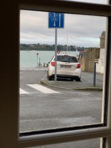 une voiture blanche garée dans une rue à côté de l'eau dans l'établissement Le Cap Solidor, à Saint-Malo
