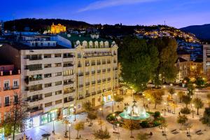 a city with a building and a fountain at night at Eurostars Puerta Real in Granada