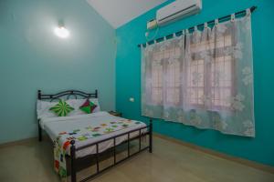 a bedroom with a bed and a blue wall at Belleville - A Peaceful Holiday Home in Madgaon