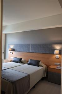 
a hotel room with two beds and two lamps at Hotel Cap Roig Nature in L'Ampolla
