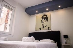 Zagreb Creative Apartments APP 1 في زغرب: غرفة نوم بسرير مع صورة لامرأة