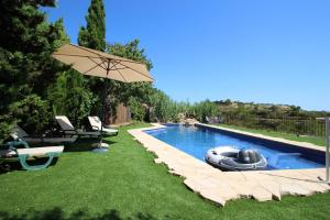 a swimming pool with an umbrella and an inflatable at Rocasol - rustic finca for nature lovers in Benissa in Benissa