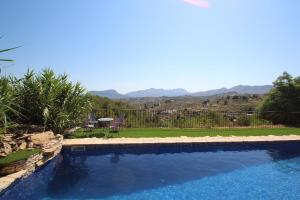 a large swimming pool with a view of the mountains at Rocasol - rustic finca for nature lovers in Benissa in Benissa