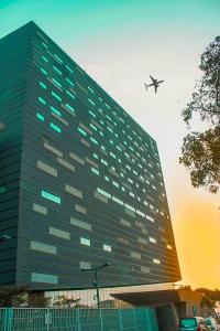 un gran edificio con un avión volando sobre él en The Nishat Hotel Johar Town, en Lahore