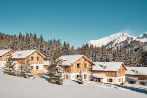 a lodge in the snow with mountains in the background at Almdorf Omlach, Fanningberg in Weisspriach