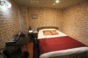 um quarto com paredes de tijolo, uma cama e uma secretária. em Gomax (Adult Only) em Yokohama