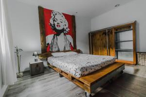 1 dormitorio con 1 cama con una pintura en la pared en The Modern & Recycled House, en Machico