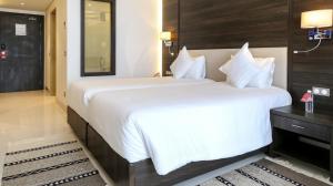una camera d'albergo con un grande letto con lenzuola bianche di Radisson Hotel Sfax a Sfax