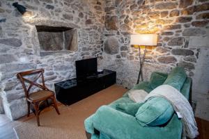 a living room with a couch and a tv in a stone wall at Casas de São Martinho in Arcos de Valdevez +49 photos