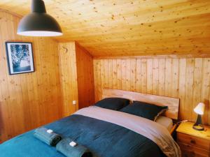 ein Schlafzimmer mit einem Bett in einer Holzhütte in der Unterkunft Hôtel Pension du Lac Bleu in La Gouille
