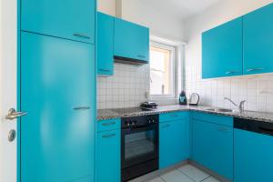 卢加诺Lido Apartments by Quokka 360 - 5 min from the centre and the Lugano Lido的蓝色的厨房,配有蓝色的橱柜和水槽