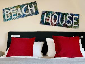 1 dormitorio con 1 cama con almohadas rojas y 2 pinturas en BEACH HOUSE-Traumwohnung in Bestlage mit herrlichem Meerblick, en Harrislee