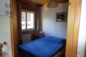 - une chambre avec un lit bleu et une fenêtre dans l'établissement Les Passereaux 2, à Saint-Gervais-les-Bains