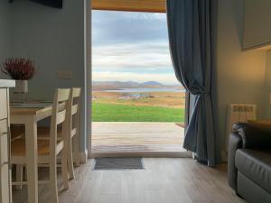 a kitchen with a table and a view of the ocean at Hebridean Holiday Cabins in Breasclete