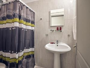 a bathroom with a sink and a shower curtain at Aeon Hotel in Laganas