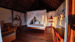 a bedroom with a bed with a mosquito net at LE TRANSAT in Ambatoloaka