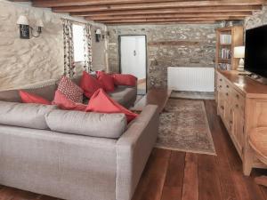 a living room with a gray couch and red pillows at Dovetail Cottage in Llangollen