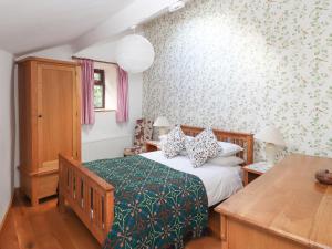 a bedroom with a bed with a green and white blanket at Dovetail Cottage in Llangollen