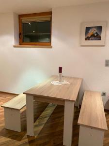 een houten tafel met een wijnglas en twee banken bij Ferienwohnung Sophia in Inzing