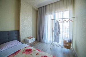 a bedroom with a bed and a window with a swing at Comfy Apartment in Tbilisi City