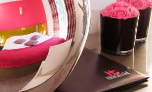 a room with a bed with pink sheets and roses at Hotel Du Golf in Saint-Étienne