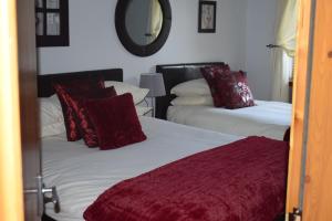 a bedroom with two beds with red pillows and a mirror at Dunroamin Self-Catering Apartment in Aviemore