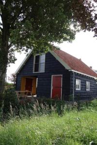 a blue house with a red door in a field at Hofje Margo in Meliskerke