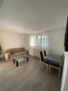 a living room with a couch and a table at Le gîte du cavalier au cœur de la Forêt/jacuzzi in Dole