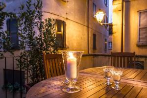 a wooden table with a candle and three glasses on it at Cernobbio Town House in Cernobbio