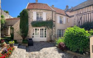 a house with a white door and a courtyard at La Maison d'Emilie - Chambres d'hôtes in Chaumes-en-Brie