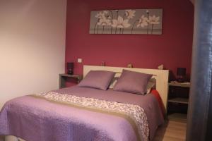 1 dormitorio con 1 cama con colcha púrpura en Maison de Tante Louise, en Mittelwihr