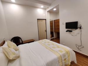 a bedroom with a bed and a tv on the wall at Hotel Surya Grande in Kudal