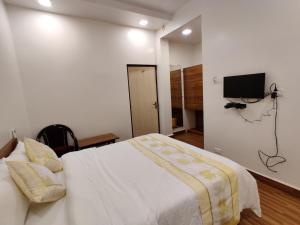 KudālにあるHotel Surya Grandeのベッドルーム1室(ベッド1台、壁掛けテレビ付)
