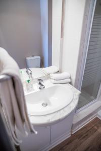 y baño blanco con lavabo y ducha. en Logis Hôtel - Auberge du Pastel - Hôtel 3 étoiles et Restaurant, en Nailloux