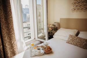a bed with a tray of food and a window at Arcadie Montparnasse in Paris