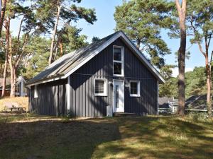 a black house with a white door in a yard at Ferienhaus Ostseeblick 236 in Baabe